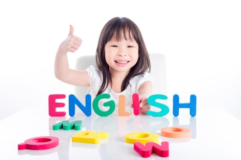 快樂的女孩舉起彩色英文字母塊的拇指