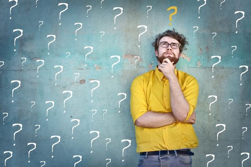 男人正在思考選擇，周圍都是問號。 為孩子選擇一個線上英語學習平台？