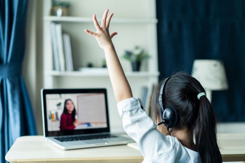 線上英語課堂上的女孩舉手參與視訊課程。