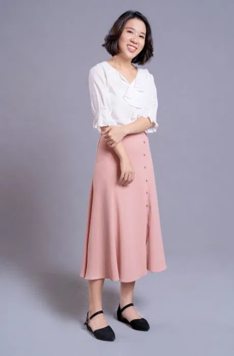 身穿白色襯衫和粉紅色中長裙的女子