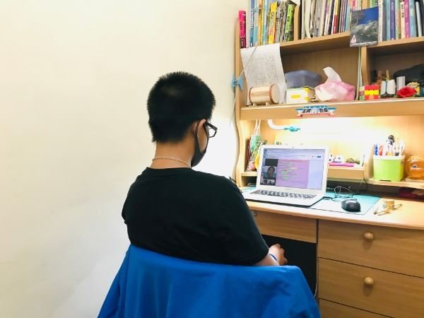學生戴著口罩在家用課桌上網課。