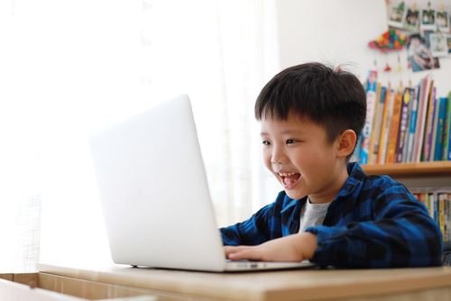 快樂的男孩用筆記型電腦學習英語