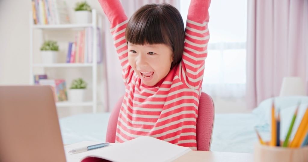 快樂的女孩在網路上學習英語,舉起雙臂慶祝。