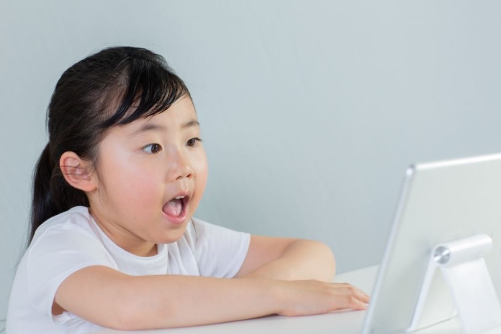 驚訝的小女孩用平板電腦學習英語