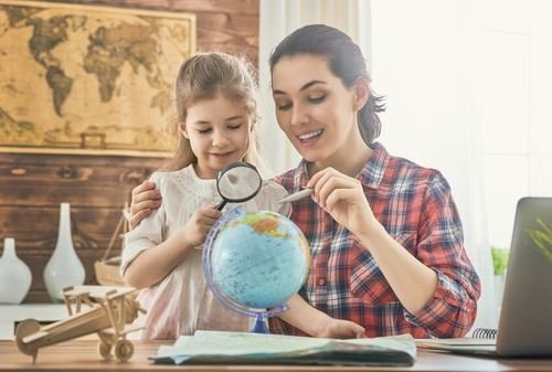 母親和女兒用放大鏡探索地球儀,並規劃一趟旅行。